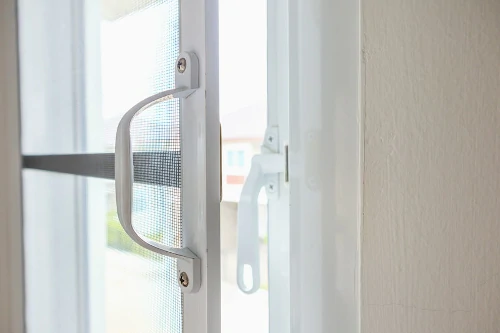 Nahaufnahme eines geöffneten Fensters mit Fliegengitter und Fenstergriff