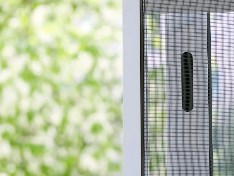 Insektenschutzgitter am Fenster mit Griff, Blick ins grüne Außenlicht