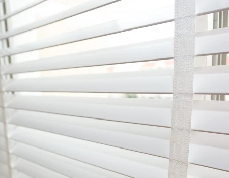 Weiße Jalousien am Fenster mit Lamellen, Sichtschutz und Tageslicht im Raum