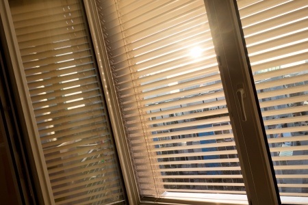 Sonnenlicht durch Jalousien am Fenster, warmes Licht im Innenraum